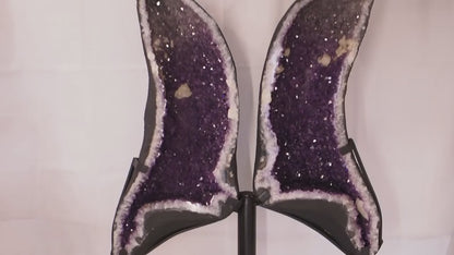 Geode angel wings formed from a split amethyst geode on metal display stand.