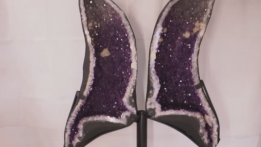 Geode angel wings formed from a split amethyst geode on metal display stand.