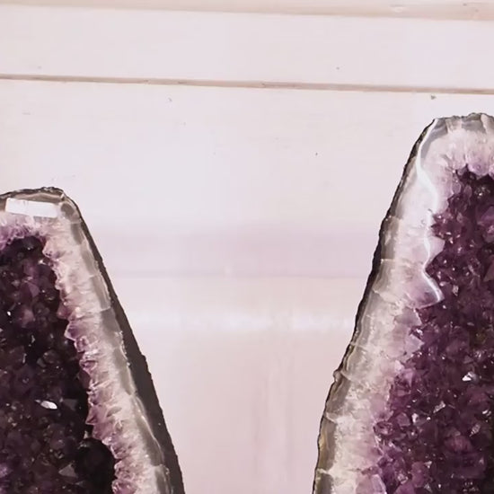 Large amethyst geode pair with deep purple crystal clusters and polished fronts.