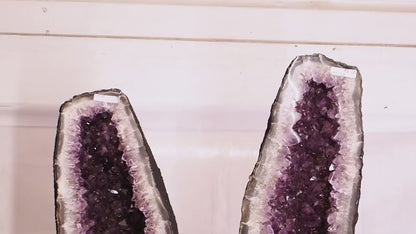 Large amethyst geode pair with deep purple crystal clusters and polished fronts.