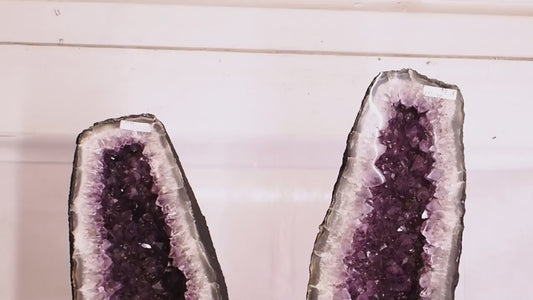 Large amethyst geode pair with deep purple crystal clusters and polished fronts.