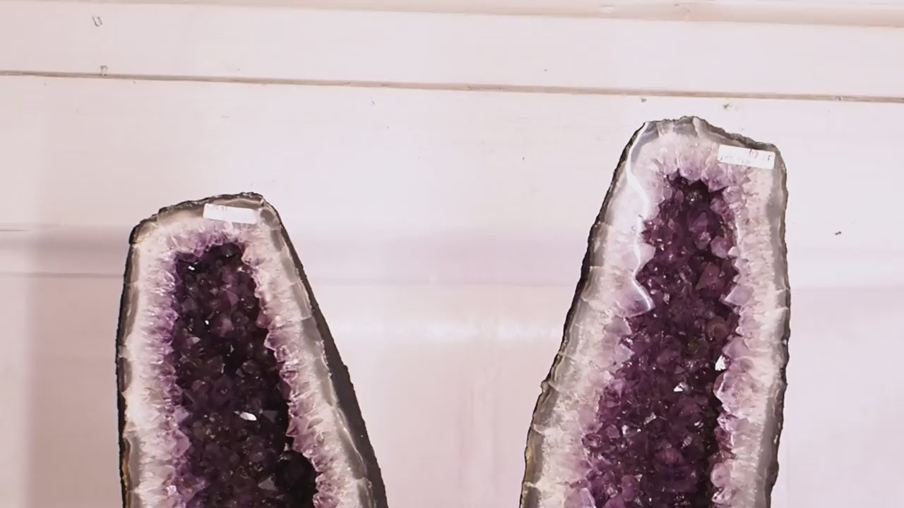 Large amethyst geode pair with deep purple crystal clusters and polished fronts.